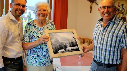 Anna Scharmer überreicht ein Bild der alten Feldernalm an die Repräsentanten der neuen Hochfeldern Alm. Foto: Knut Kuckel